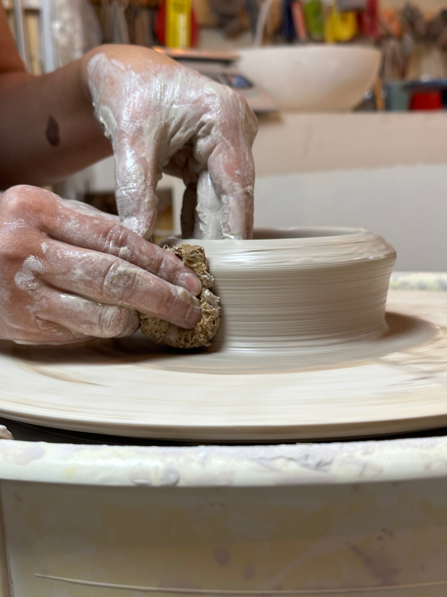 Pulling up the walls of the clay to lift and shape the piece